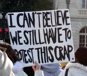 Protestor's sign: I can't believe we still have to protest this crap